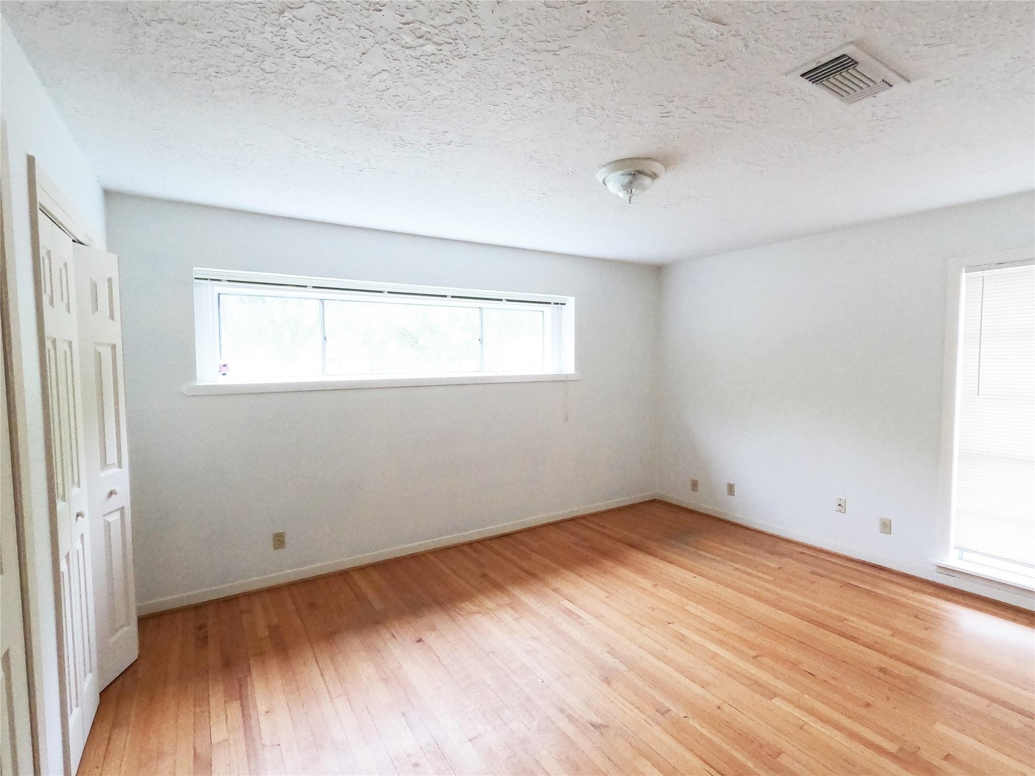 5231 Beechnut Street Houston, TX 77096 - Photo 6 of 19 an empty room with wooden floor and windows