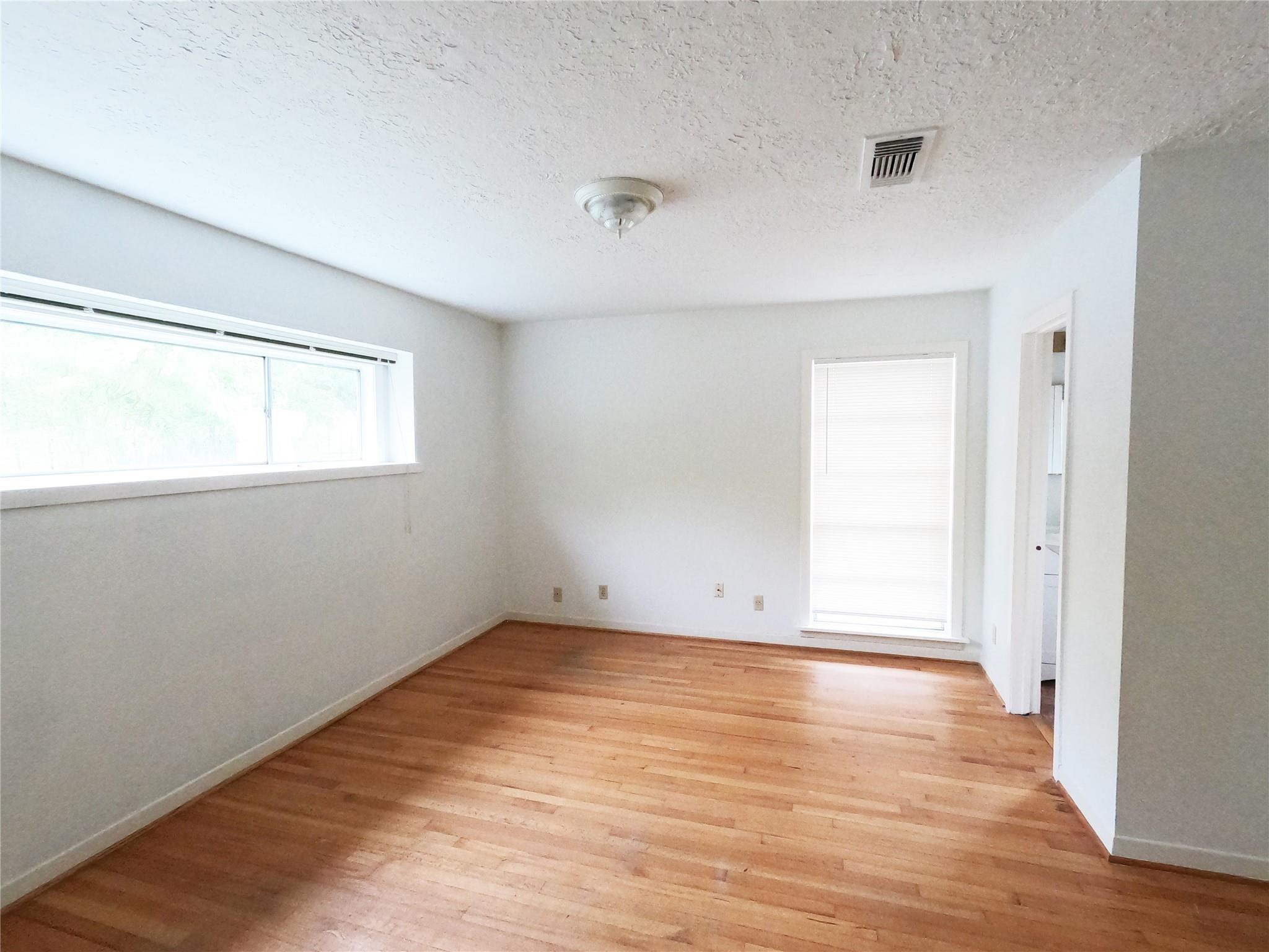 5231 Beechnut Street Houston, TX 77096 - Photo 7 of 19 an empty room with wooden floor and windows