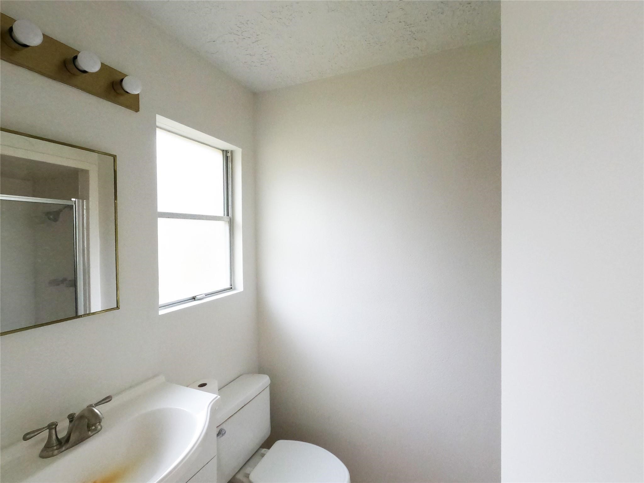5231 Beechnut Street Houston, TX 77096 - Photo 8 of 19 a bathroom with a sink mirror and toilet