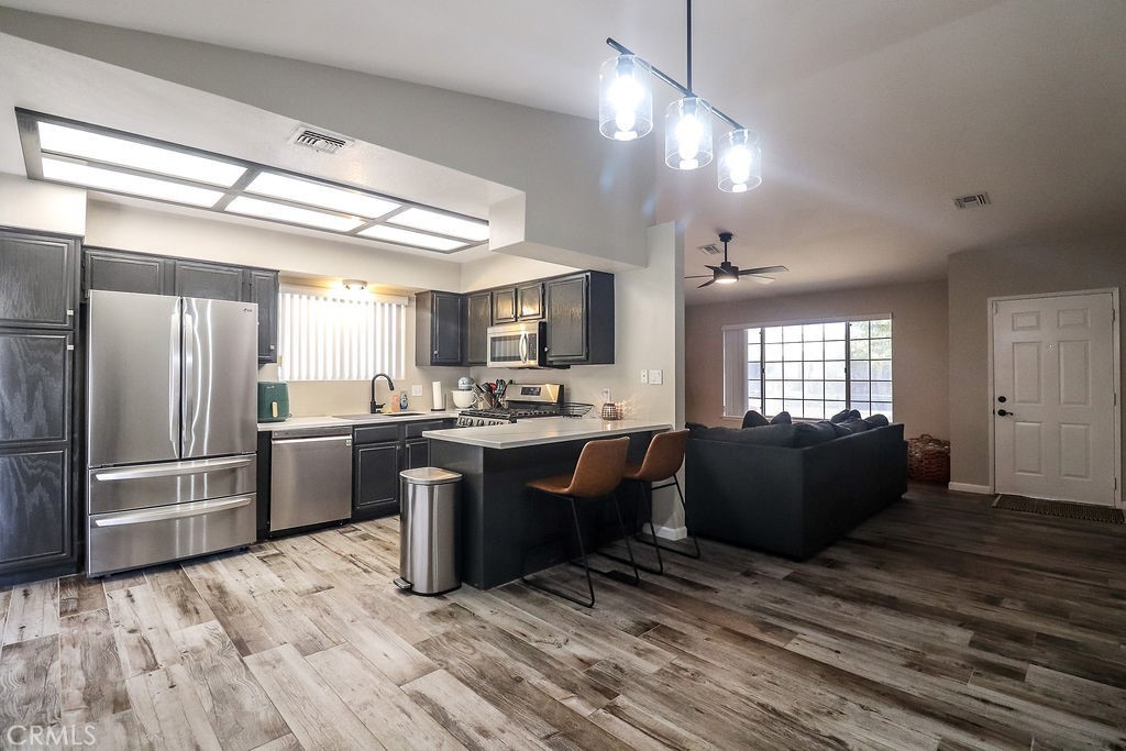 1330 Santa Fe Circle Needles, CA 92363 - Photo 11 of 28 a kitchen with stainless steel appliances kitchen island granite countertop a refrigerator a sink dishwasher a stove and a dining table with wooden floor