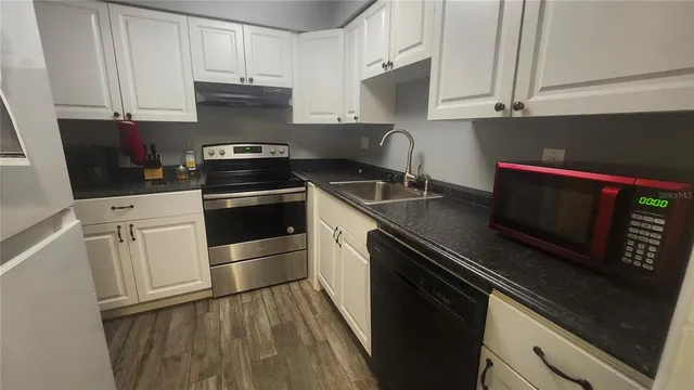 a kitchen with granite countertop a stove microwave and sink