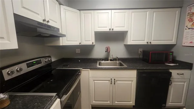 a kitchen with white cabinets and appliances