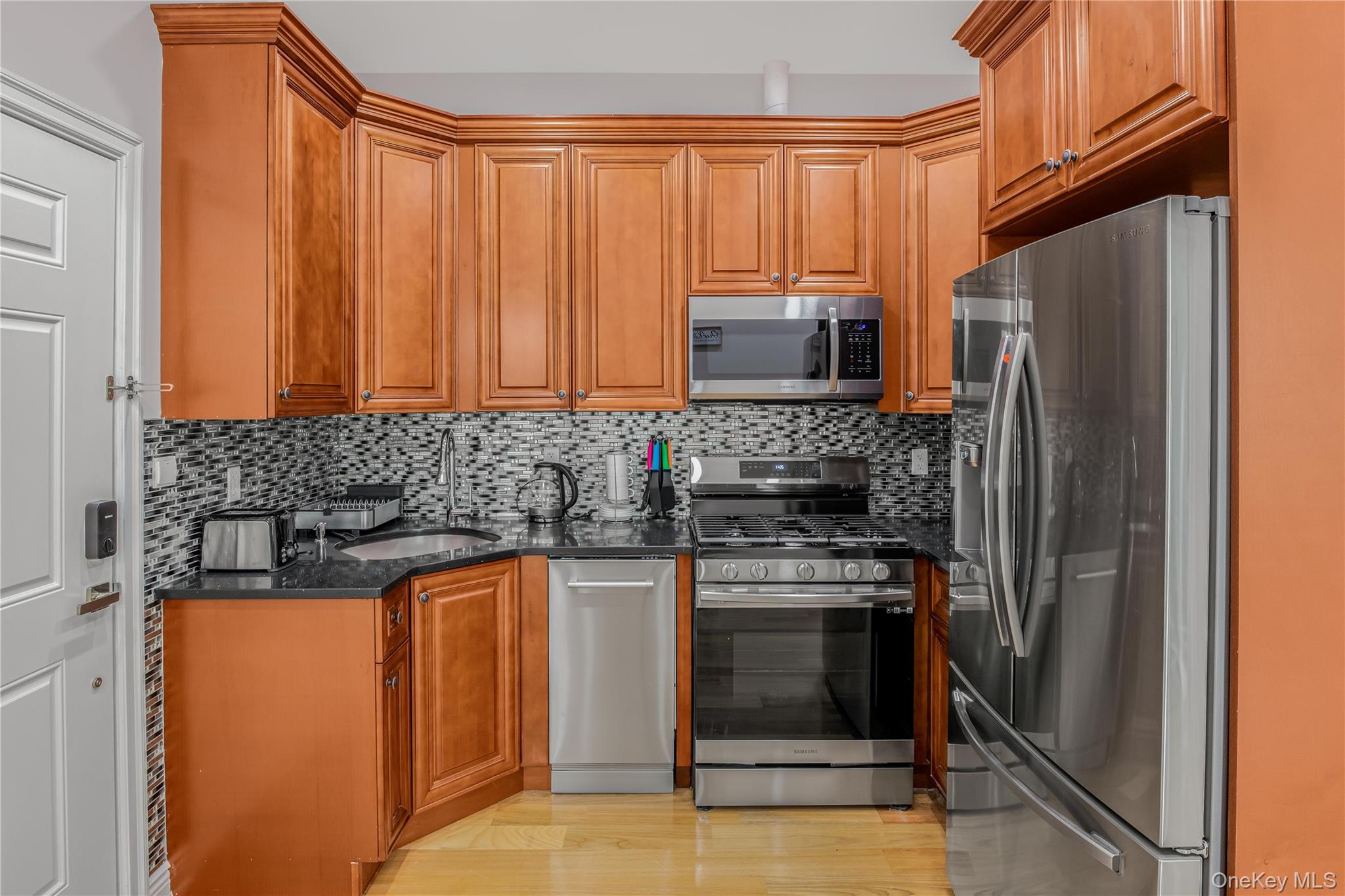 43-47 44th Street, Unit 3F Queens, NY 11104 - Photo 5 of 17 a kitchen with granite countertop a refrigerator stove and microwave