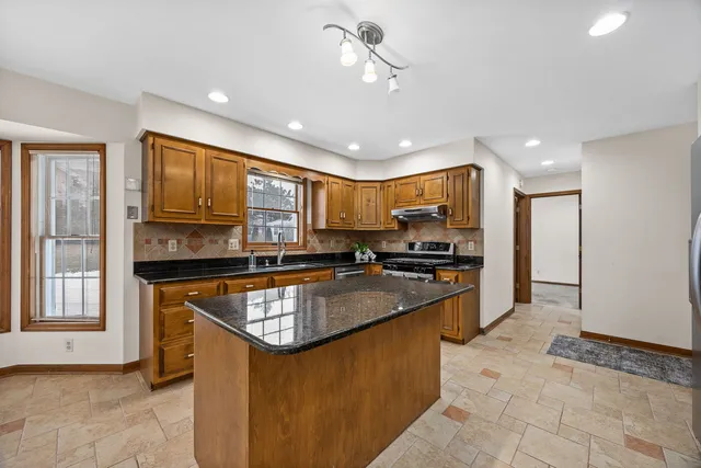 a kitchen with stainless steel appliances granite countertop a stove sink refrigerator and cabinets