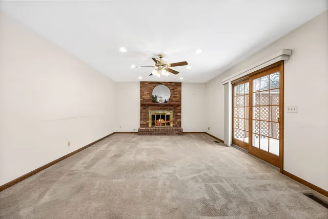 an empty room with chandelier fan and windows