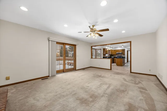 an empty room with chandelier fan and windows