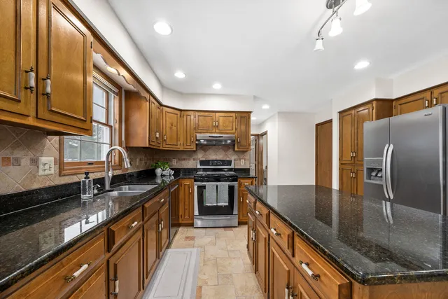 a kitchen with stainless steel appliances granite countertop a sink a stove and a refrigerator