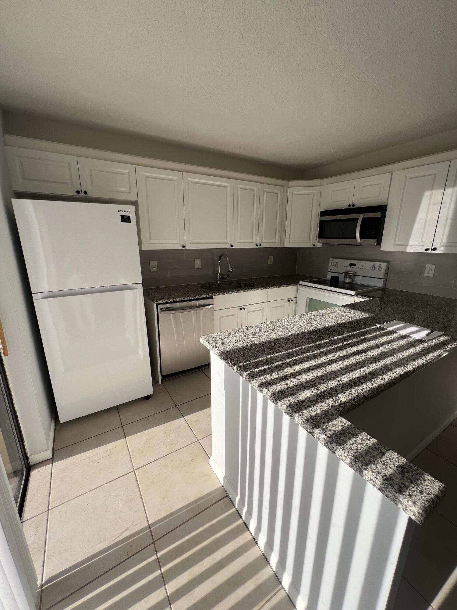 731 Springdale Circle Palm Springs, FL 33461 - Photo 11 of 20 a kitchen with a refrigerator and a stove top oven