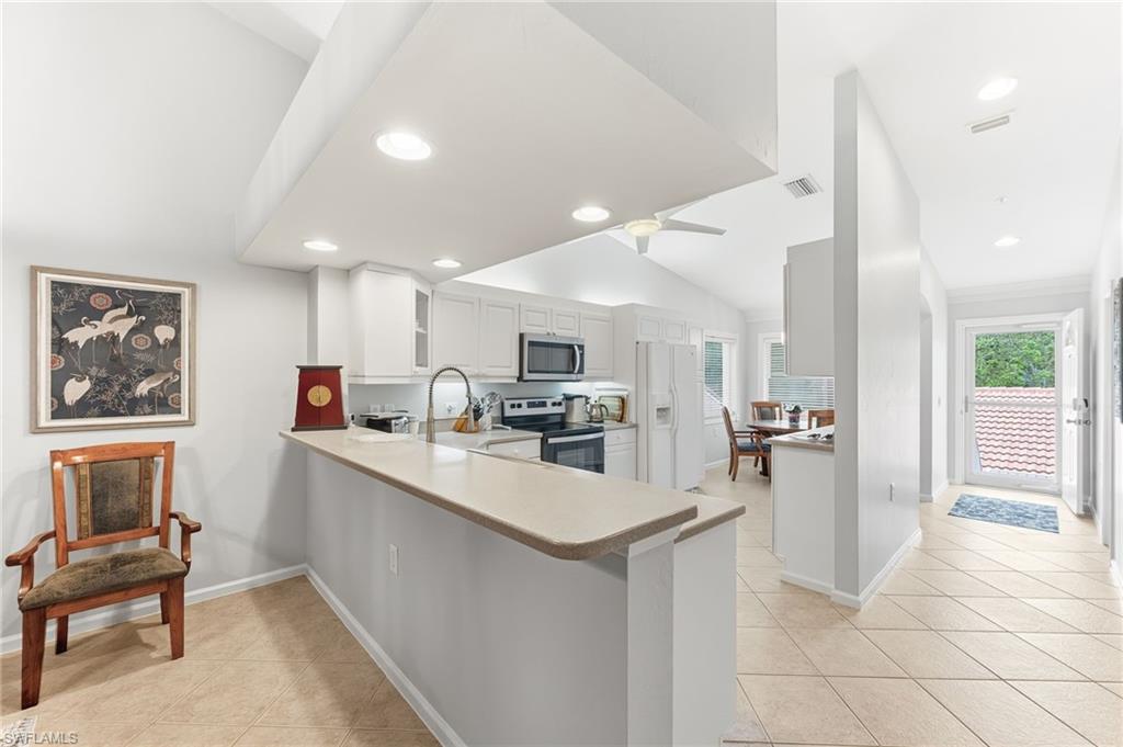 6840 Beach Resort Drive, Unit 16 Naples, FL 34114 - Photo 2 of 49 Kitchen with stainless steel appliances, a peninsula, light countertops, white cabinets, and vaulted ceiling