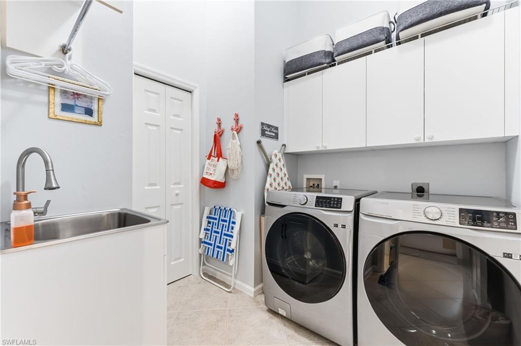 6840 Beach Resort Drive, Unit 16 Naples, FL 34114 - Photo 33 of 49 Laundry area featuring washing machine and dryer, cabinet space, and light tile patterned floors
