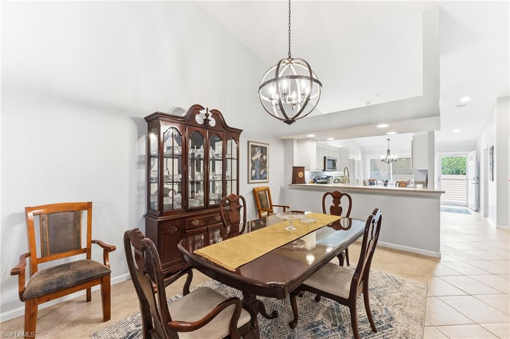 6840 Beach Resort Drive, Unit 16 Naples, FL 34114 - Photo 5 of 49 Dining space featuring suspended lighting, light tile patterned flooring, and vaulted ceiling