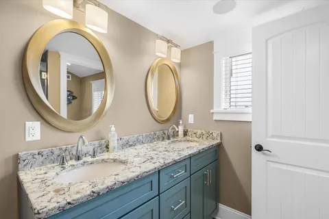 a bathroom with a granite countertop double vanity sink and a mirror