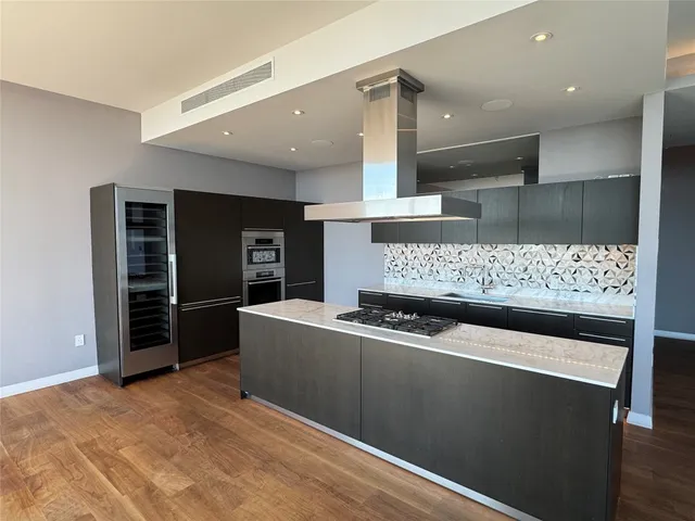 a living room with stainless steel appliances kitchen island granite countertop a refrigerator and a stove
