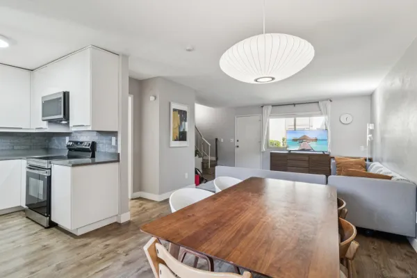 a large kitchen with stainless steel appliances kitchen island granite countertop a refrigerator a stove a sink a dining table and chairs with wooden floor