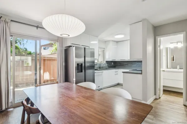a large kitchen with sink a refrigerator and white cabinets