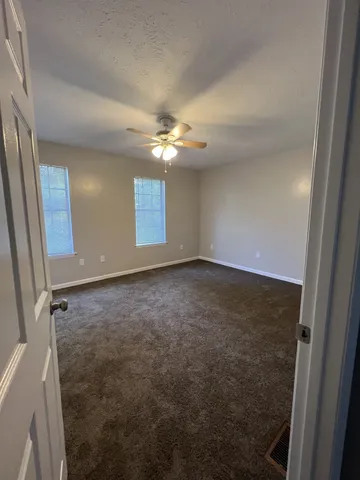 an empty room with windows and fan