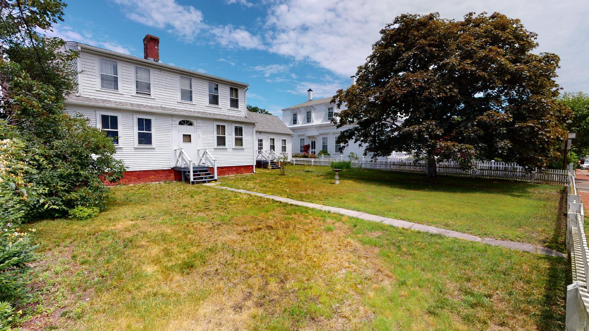 580 Commercial Street Provincetown, MA 02657 - Photo 2 of 58 a front view of a house with a yard table and chairs
