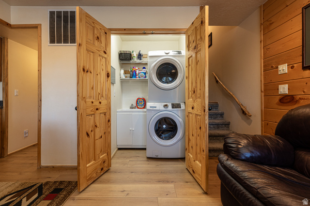 1505 West Elk Ridge Drive Alton, UT 84710 - Photo 34 of 53 Laundry room featuring stacked washer / dryer, light wood-type flooring, and wood walls