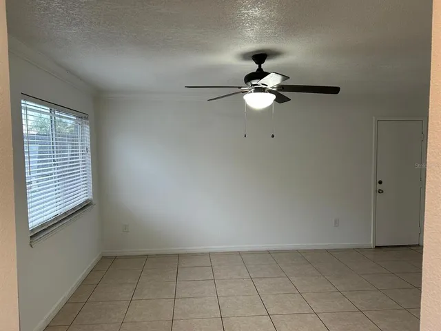 a view of an empty room with a ceiling fan and window