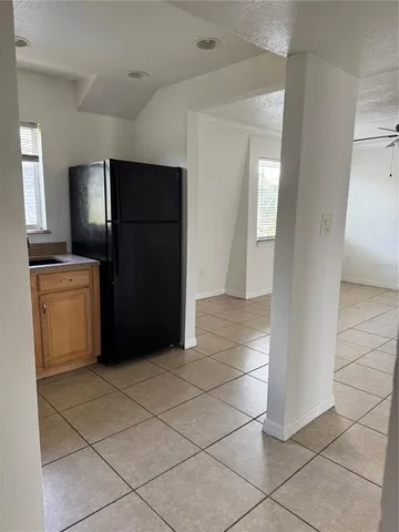 a view of a refrigerator in kitchen and an empty room in wooden floor