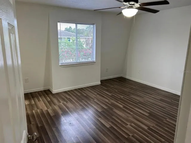 an empty room with wooden floor fan and windows