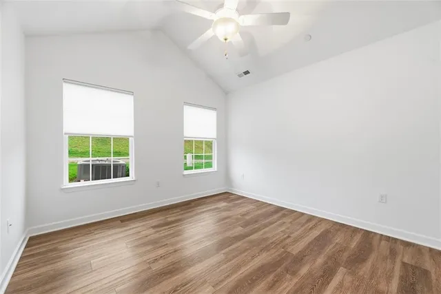 an empty room with wooden floor and windows