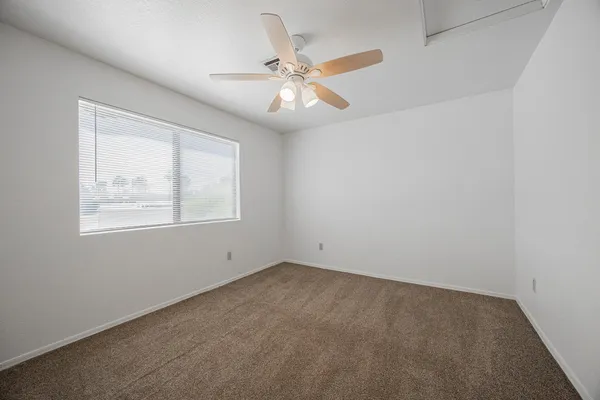 an empty room with a window and a fan
