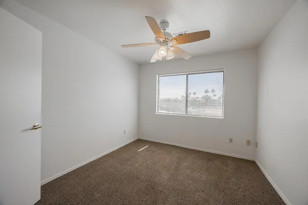 an empty room with a window and ceiling fan