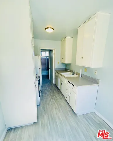 a large white kitchen with sink and refrigerator