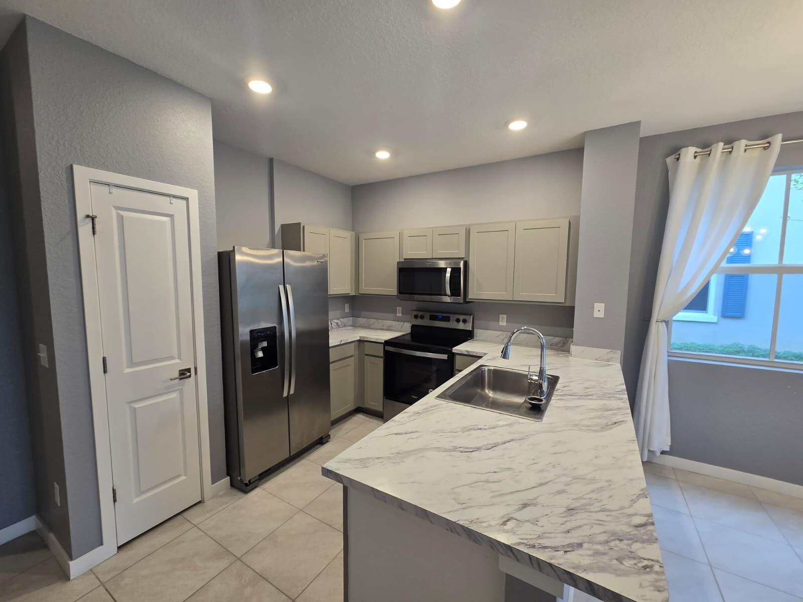 140 Bandol Street Riviera Beach, FL 33404 - Photo 11 of 42 a kitchen with stainless steel appliances granite countertop a refrigerator and a sink