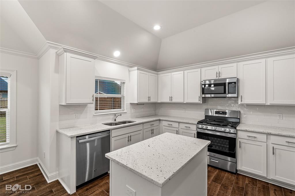 304 Prien Lk Loop Bossier City, LA 71111 - Photo 18 of 39 Modern kitchen featuring white shaker cabinetry, speckled countertops, stainless steel appliances, a center island, and wood-finish flooring