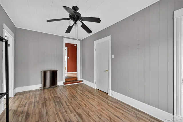 a view of empty room with wooden floor and fan