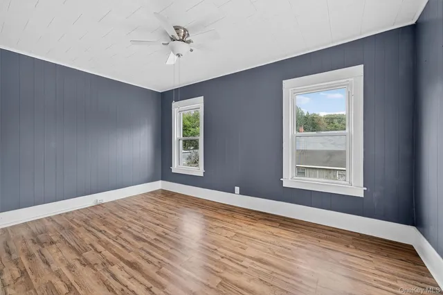 a view of an empty room with a window and wooden floor