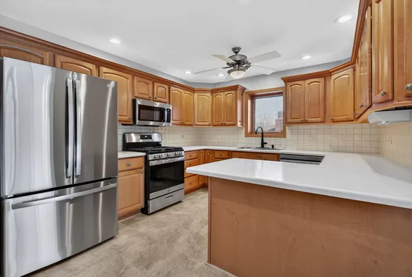 a kitchen with stainless steel appliances granite countertop a refrigerator a sink a stove a microwave and wooden cabinets