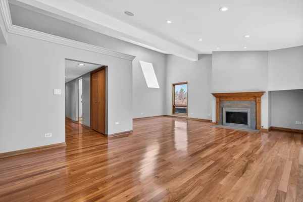 a view of an empty room with wooden floor fireplace and a window