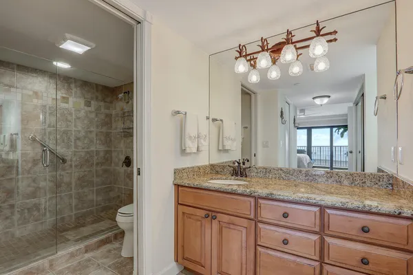 a bathroom with a granite countertop sink a mirror and a shower