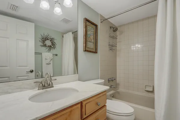 a bathroom with a granite countertop sink a toilet a mirror a vanity and shower