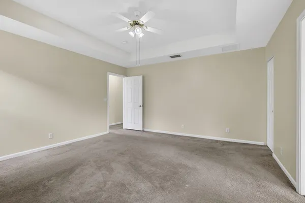 an empty room with windows and ceiling fan