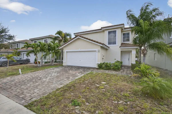 a view of a house with a yard and palm trees