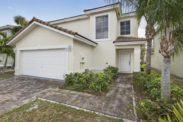 a view of a white house with a yard and plants