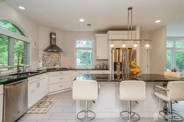 a kitchen with stainless steel appliances granite countertop a sink a stove and a wooden floors