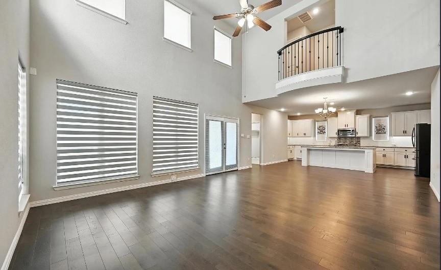 12559 Ravine Creek Road Frisco, TX 75035 - Photo 10 of 33 Unfurnished living room featuring a ceiling fan, suspended lighting, dark wood finished floors, and a high ceiling