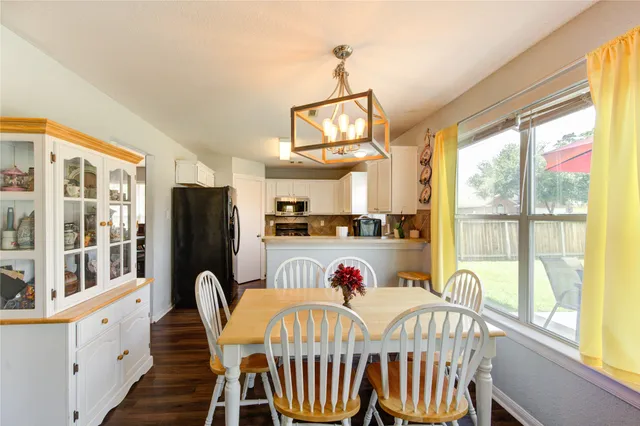 a view of a dining room with furniture a chandelier and a window