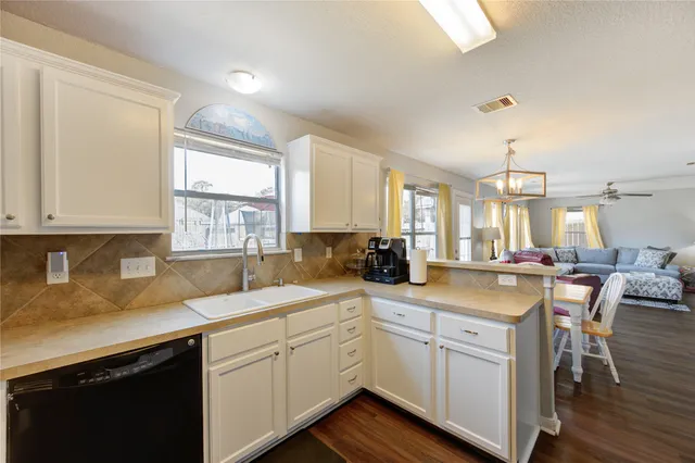 a kitchen with a sink dishwasher a stove and white cabinets with wooden floor