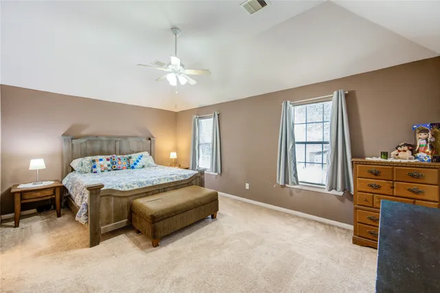 a spacious bedroom with a bed a dresser and with the dresser