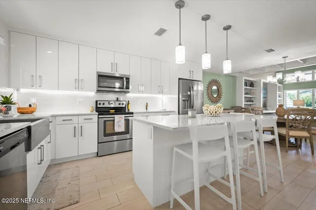 a kitchen with stainless steel appliances kitchen island granite countertop a table chairs sink and cabinets