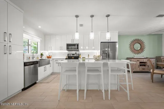 a kitchen with stainless steel appliances a refrigerator a stove a dining table and chairs