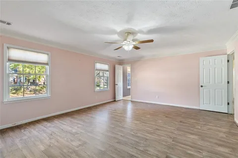 a view of an empty room with a window and wooden floor