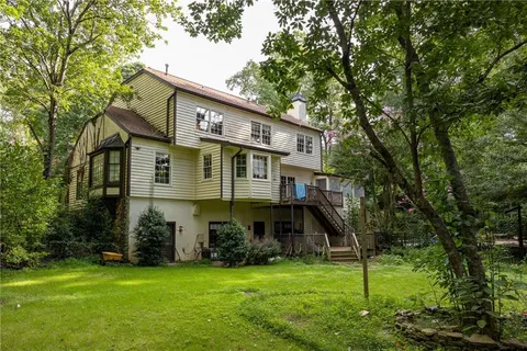 a view of a house next to a big yard and large trees