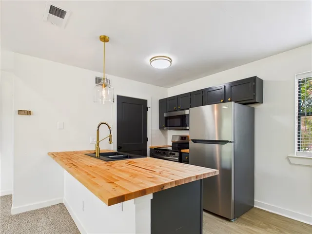 a kitchen with stainless steel appliances granite countertop a refrigerator a sink and a stove